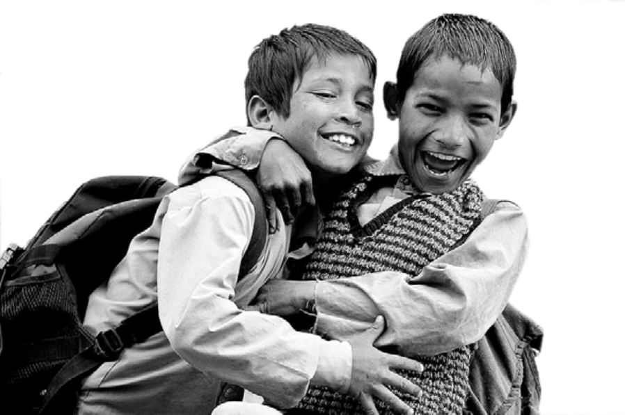 Two smiling schoolboys with backpacks embracing